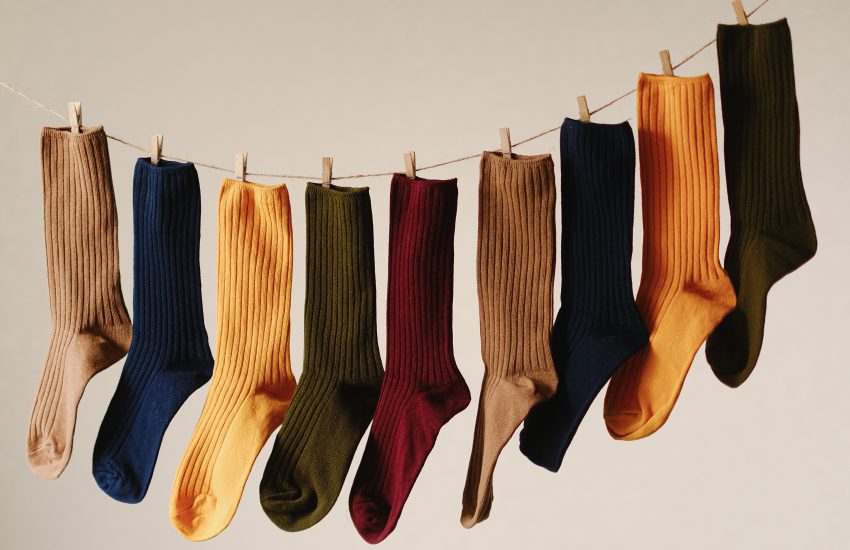Photo shows different colored socks hanging on a laundry line.
