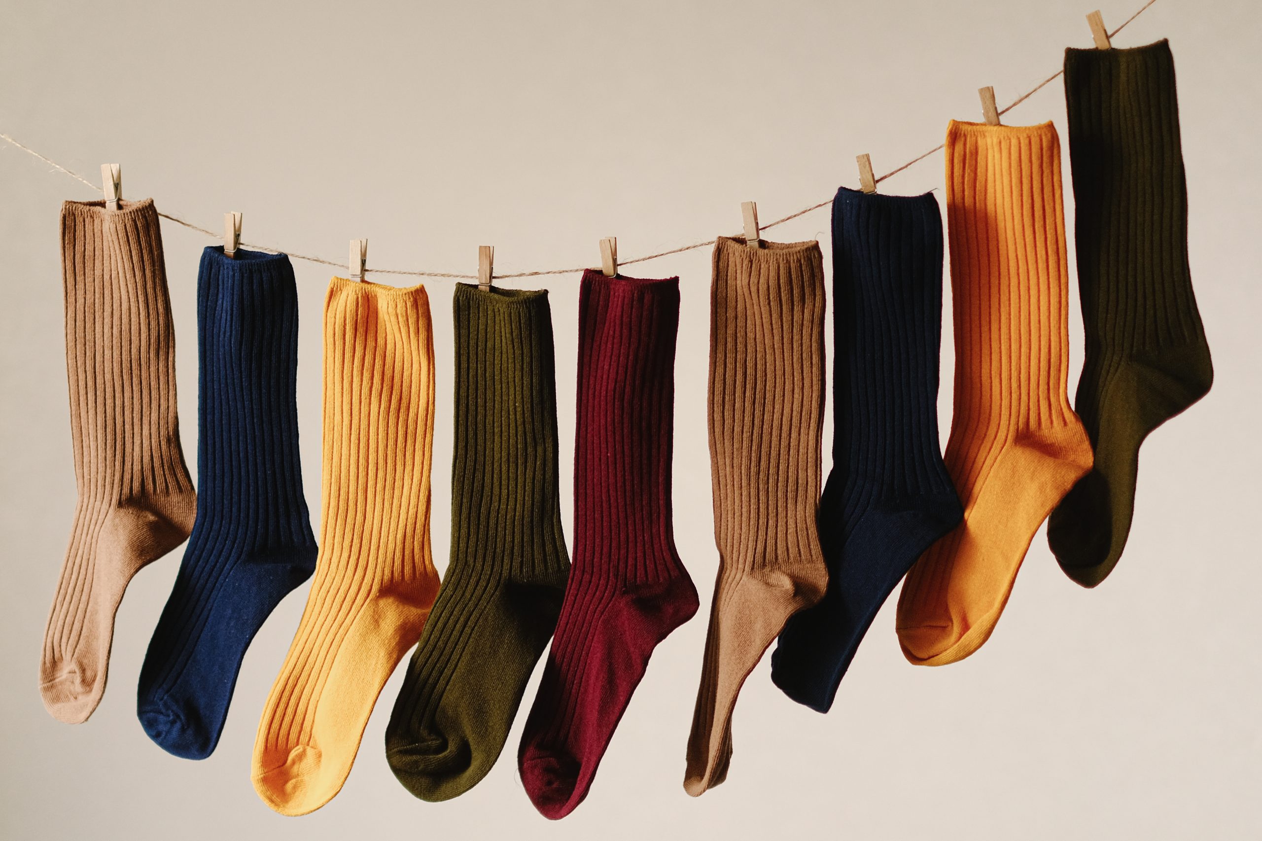 Photo shows different colored socks hanging on a laundry line.