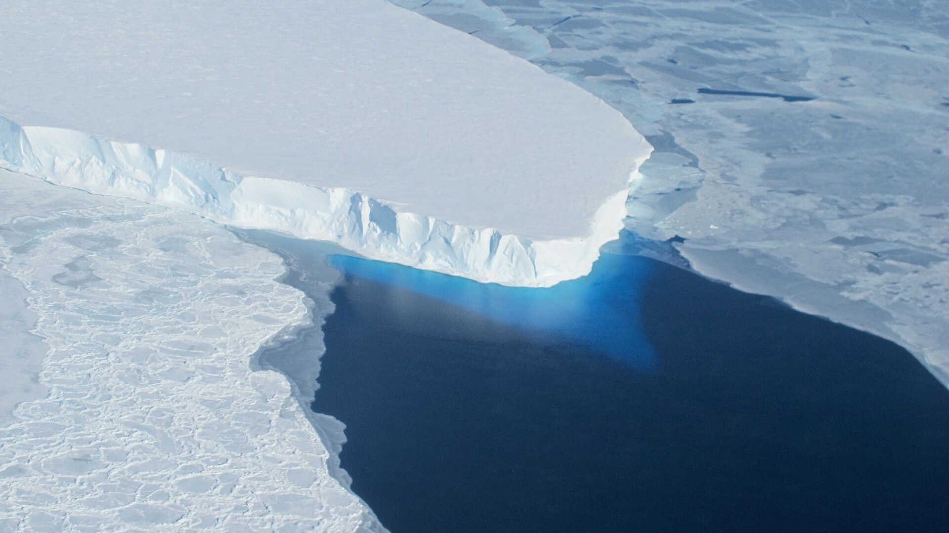 Aerial photo shows melting glacier with large crack in the middle.